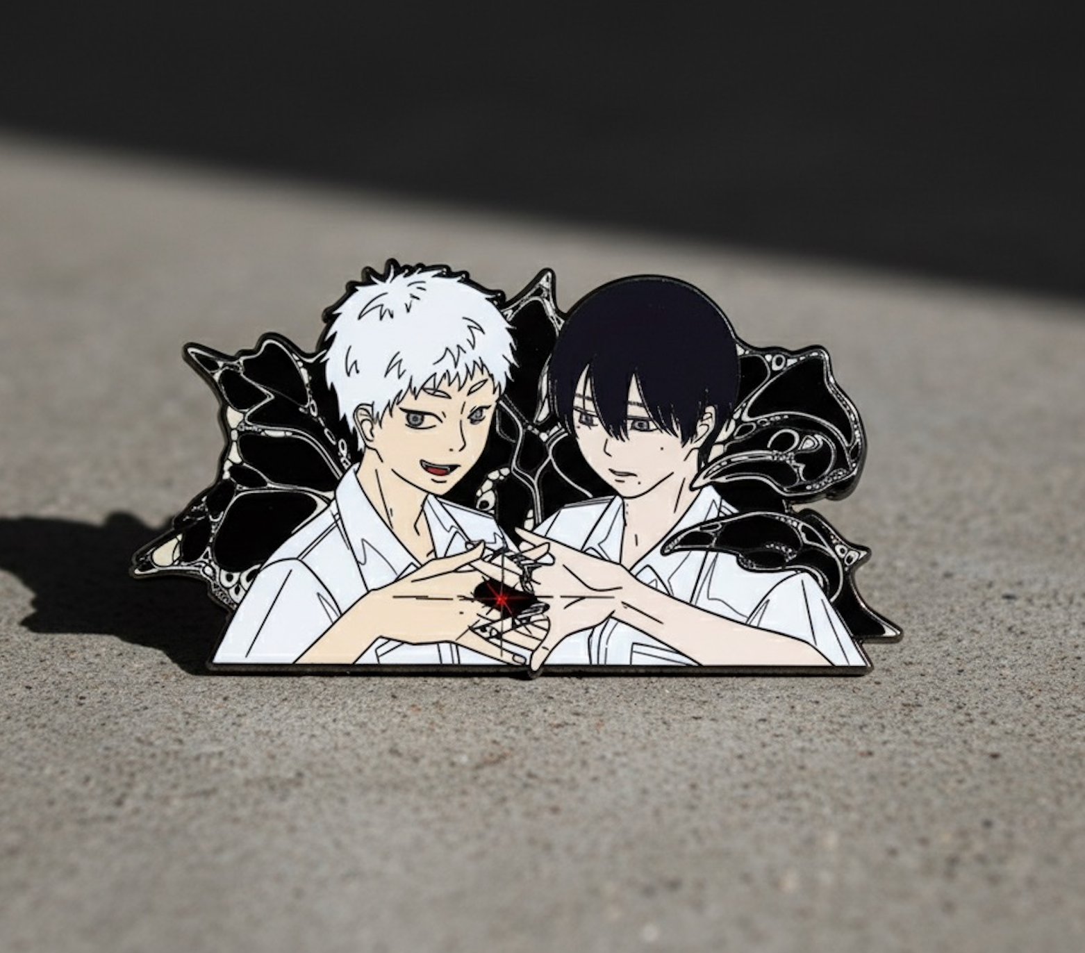 Black-plated enamel pin of two boys with butterfly wings and fox window, dark aesthetic collectible by Pinverse Studio.